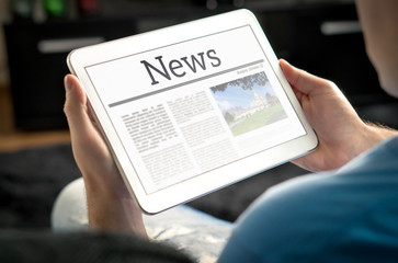 Man reading the news on tablet at home. Imaginary online and mobile news website, application or portal on modern touch screen display. Holding smart device in hand. - obrazy, fototapety, plakaty