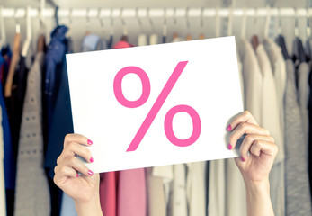 Sale, bargain and reduced cheap prices in clothes store. Percent symbol on paper. Woman holding...