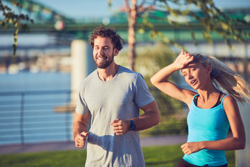Obraz premium Modern woman and man jogging / exercising in urban surroundings near the river.