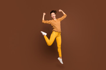 Fototapeta na wymiar Full length body size photo of cheerful positive excited nice sweet powerful trendy girlfriend showing you her muscles while jumping up with excited facial expression isolated brown pastel color