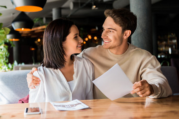 selective focus of happy man and woman smiling in restaurant