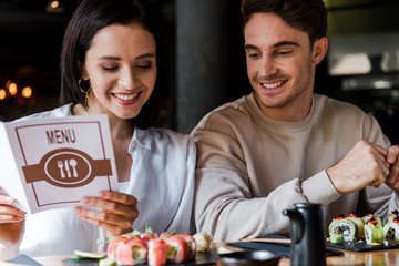 handsome man sitting near happy woman with menu in hands