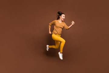 Fototapeta na wymiar Full length body size photo of cheerful sweet pretty cute nice charming girl urgent for sales and discounted goods wearing yellow pants trousers isolated over brown pastel color background