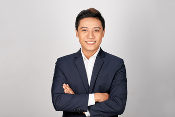 Happy Asian young businessman standing cross-armed on white background