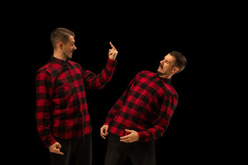 Young handsome man arguing with himself on black studio background. Concept of human emotions,...