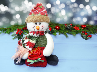 christmas snowman decoration and garland lights on vintage wooden background