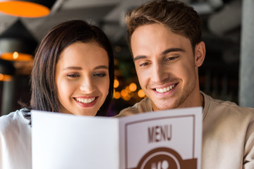 selective focus of happy man and cheerful woman holding menu