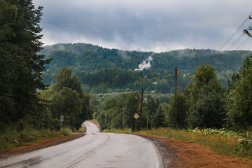 A road in a rainy day. Heavy clouds are above