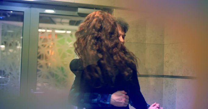 Young couple dancing latin dance in office doorway. Candid shot through glass dor. Slow motion, 4K UHD