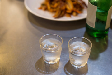 Soju bottle and small glass cup. Alcoholic Clear Distilled Korean Soju.