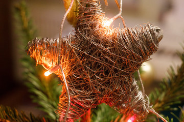 New year handmade star hanging on a Christmas tree..Holiday background with sparkle light, star and spruce. Vintage toy on  tree and flickering garland. Happy holiday.