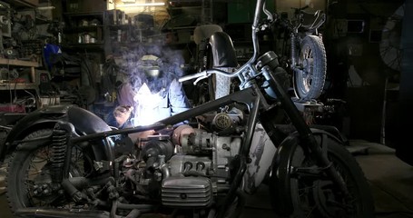 Close up shot of experienced man working in custom made motorcycle workshop. - Powered by Adobe