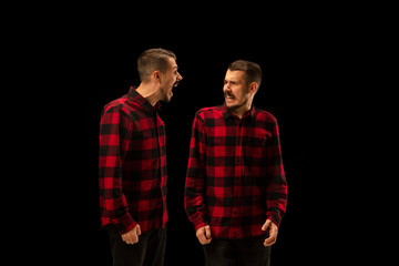 Young handsome man arguing with himself on black studio background. Concept of human emotions, mental issues, internal conflict, split personality. Half lenght portrait. Negative space.