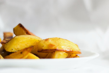 Golden fried potatoes on a white plate on a light background of cotton fabric, Studio photo, light from the window, selective focus