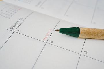 ball pen pointed at New Year's Day on opened planner page