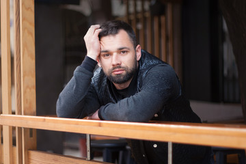 Pensive bearded young man outdoors in the afternoon in the city.