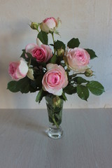 A bouquet of pink roses stands in a glass vase.