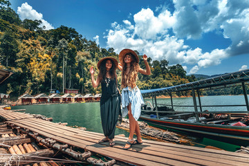 Two beautiful cheerful girls with vietnamese hats on tropical background