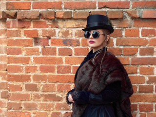 girl in a black dress on a background of a brick wall in autumn