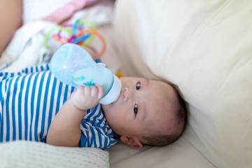 A Pretty baby boy drinking milk from bottle lying