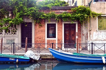Fototapeta na wymiar Venetian pedestrian street along the canal with boats and houses