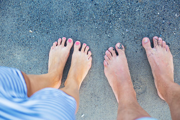 legs lovers sitting on the beach in the water of sea