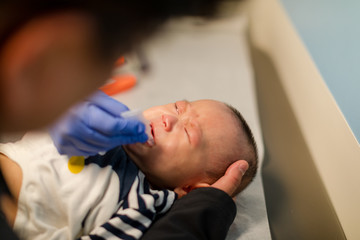 Little baby boy eating rotavirus vaccine at hospital