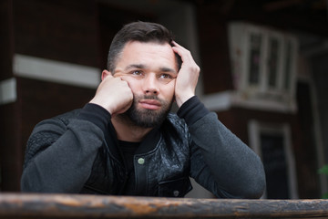 Fototapeta premium Pensive bearded young man outdoors in the afternoon in the city.
