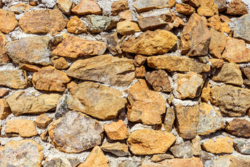 Stone wall with cement. Decorative uneven cracked stone is a real stone wall.