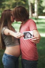 Vertical photo. A happy married couple is holding in their hands a snapshot of an ultrasonic study...