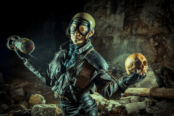 Fototapeta premium Soldier woman with the bomb in one hand and skull in another on the ruined background.