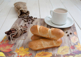 buns with a cup of coffee and cinnamon sticks