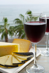 Red wine served in glasses with spanish cheese in lounge bar with sea view and palm trees