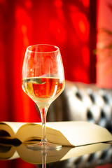 English retro style room with leather chair, open book and glas of white wine