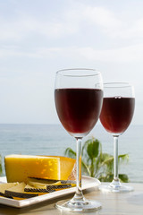 Red wine served in glasses with spanish cheese in lounge bar with sea view and palm trees