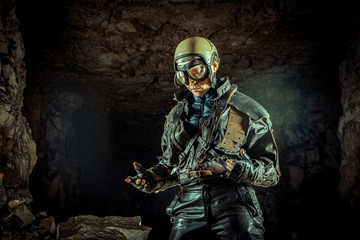 Beautiful woman soldier in leather clothing on the ruined background. War concept.