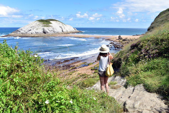 Tourist girl taking the photos of the landscape, Playa de Covachos Beach in Liencres Natural Park, Santander, Cantabria 