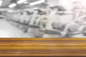 Empty wooden board space platform with blur fitness gym equipment background