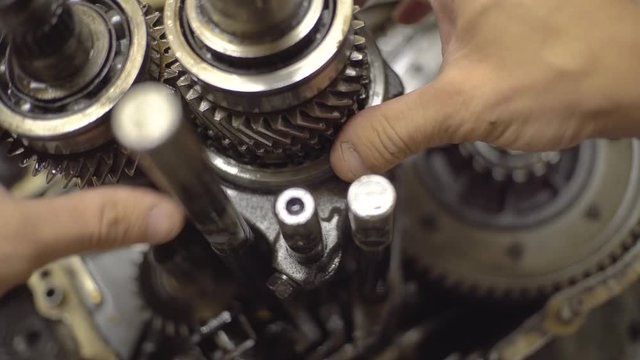 Open gearbox. mechanisms are spinning. gear engages, hand rotates gear.