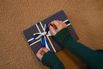 Female hands placing the loop of a blue gift box.