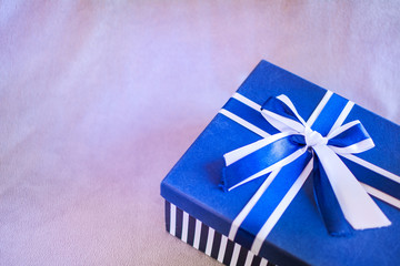 Nice gift box with blue and white bow, isolated on pink background. Copyspace left.