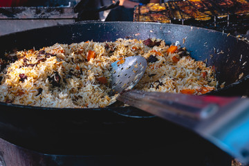 The preparation of traditional Uzbek pilaf with meat, carrots, garlic and spices. Shallow depth of...