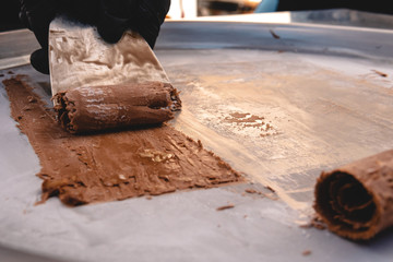 The process of making stir-fried ice cream rolls at freeze pan. Rolled ice cream, handmade dessert from milk, chocolate. close-up selective focus