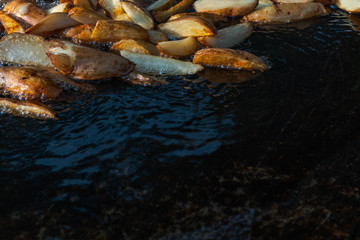 Roast potatoes in a large pan. Delicious food at the festival. Field kitchen at the hearth. lovely delicious and appetizing, yummy, black background side for copy space, text or logo