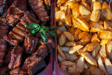 Top view, large dishes with a large number of fried potatoes and grilled steaks, appetizing food on a food court. background texture