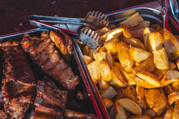 Top view, large dishes with a large number of fried potatoes and grilled steaks, appetizing food on a food court. background texture
