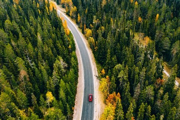 Aerial view of autumn color forest in the mountains and a road with car in Finland Lapland.