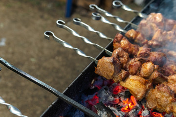 Fresh meat on a steel skewer in a smoke at brazier, diagonal arrangement, selective focus place for text, appetizing food at food court