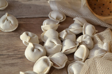 homemade dumplings, pelmeni, ravioli on shabby wooden table, close up