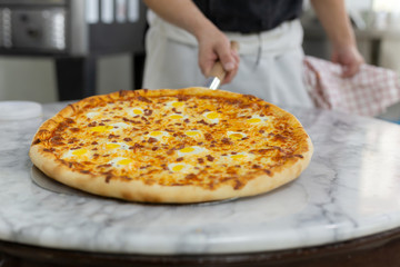 Chefs hand holding hawaiian pizza on wooden board